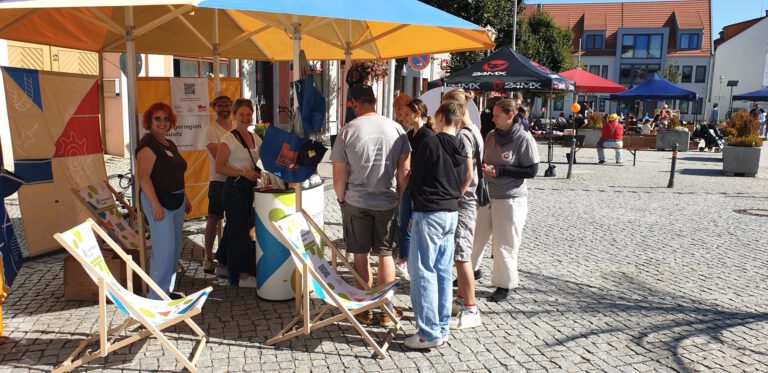 Eine Gruppe Interessierter steht am Mitmachstand der Bürgerregion Lausitz beim Tag der Nachbarn in herberg Elster