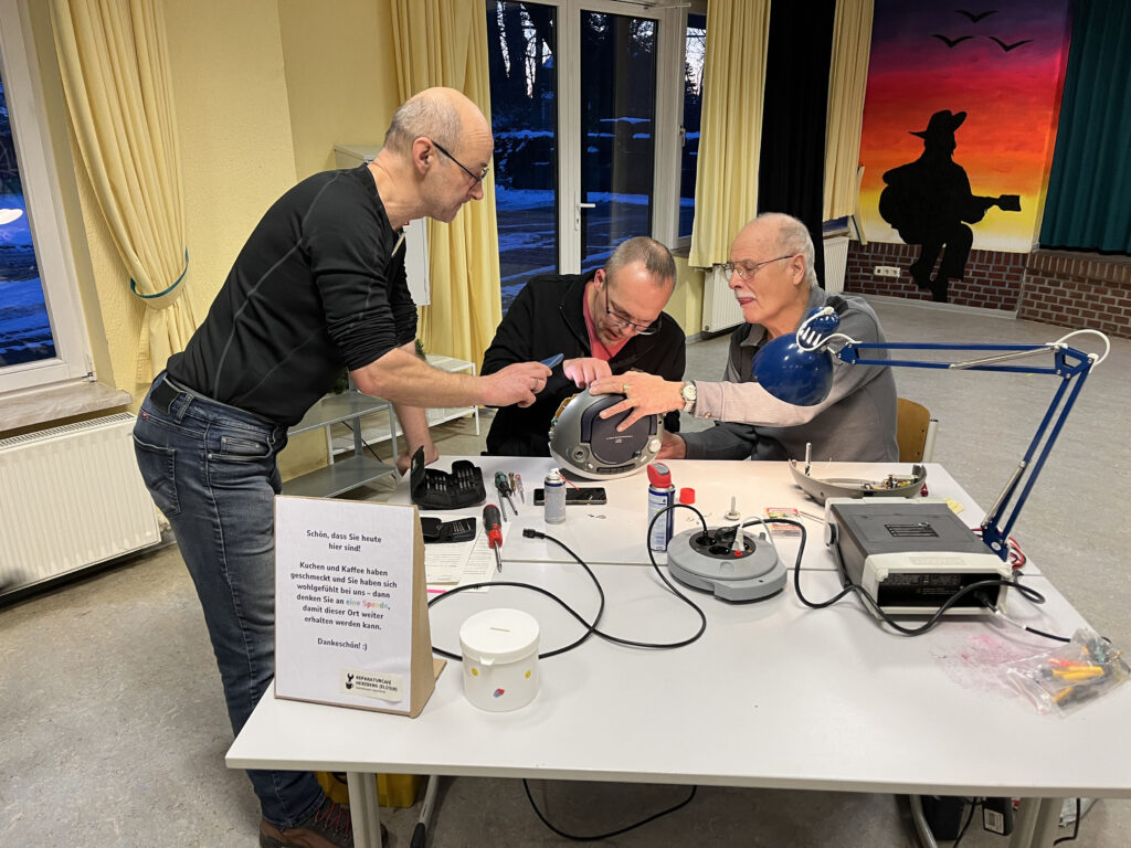 Drei Männer arbeiten an einem CD Radio