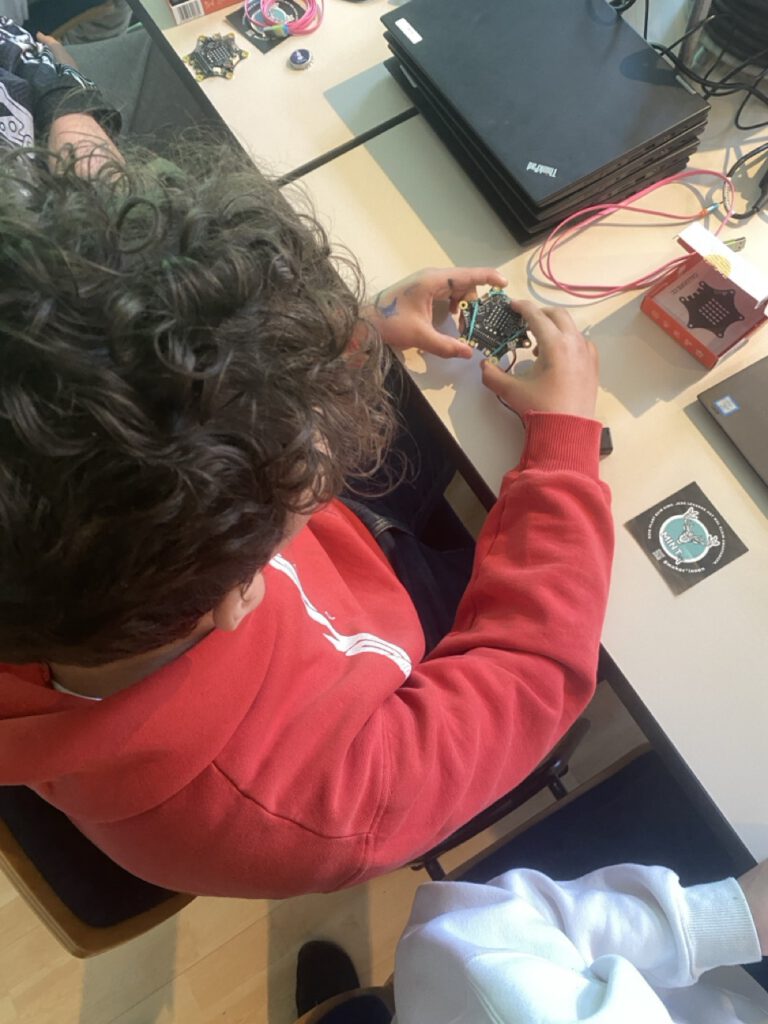 Ein Kind von oben, das gerade einen Calliope Microcontroller in der Hand hält