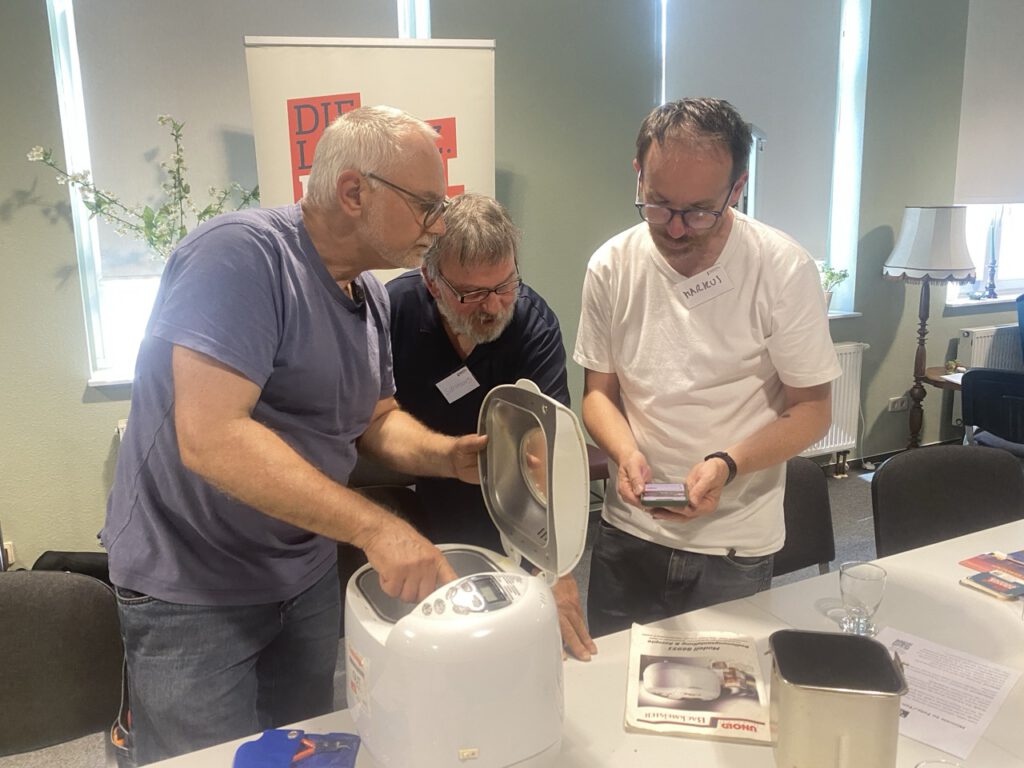 Drei Männer reparieren einen Brotbackautomat